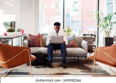 Businessman Sitting On Sofa Working On Laptop At Desk In Shared Workspace Office