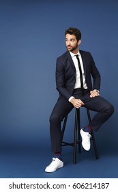 Businessman Sitting On Stool In Blue Studio