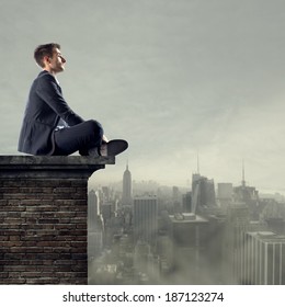 Businessman Sitting On Top Of A Building Looking Far Away With Cityscape On Backgound.