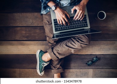 businessman sitting on wooden floor with coffee cup and glasses using laptop working at home to send and send reply to email Message customer service