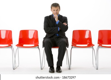 Businessman Sitting In Row Of Empty Chairs