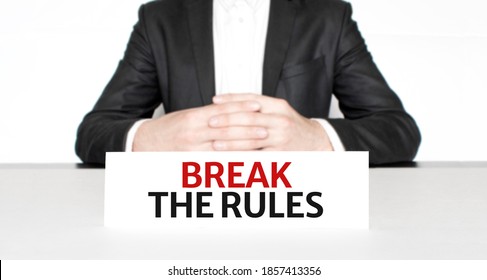 Businessman Sitting At The Table And Signboard With Text Break The Rules . Business Concept