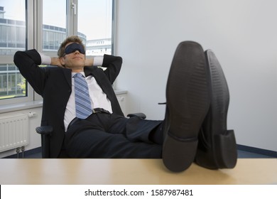 Businessman Sleeping With Feet Up On Desk