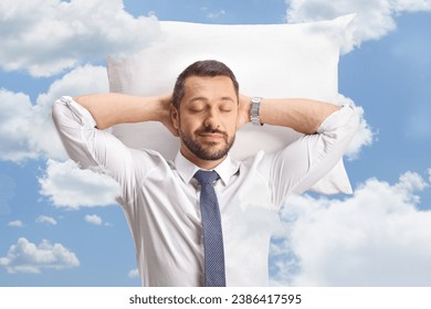 Businessman sleeping on pillow among clouds in the blue sky