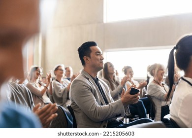 Businessman with smart phone clapping in conference audience - Shutterstock ID 2215205603