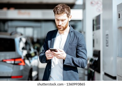 Businessman With Smart Phone During The Car Refueling At The Gas Station