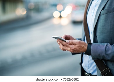 Businessman with smartphone in a city.