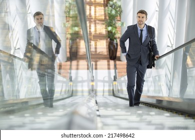 Businessman smiling with his own reflection at the escalator