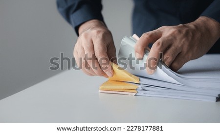 Businessman sorting stacks of department meeting papers, document management in corporate office. Office document management and storage concept.