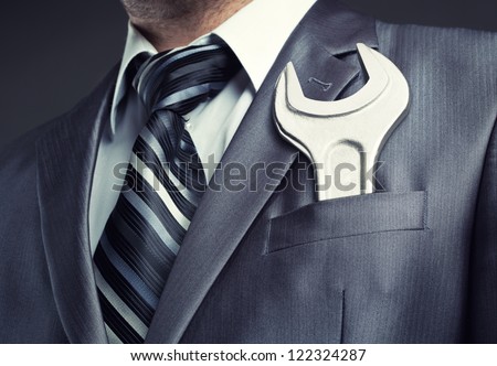 Businessman with spanner in suit pocket