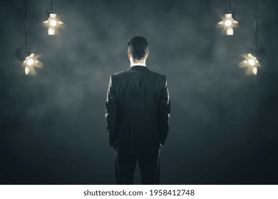 Businessman Speaker Back On Abstract Background With Spotlights On The Sides In Smoke