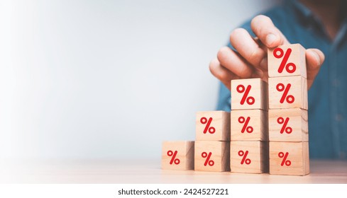 Businessman stacking increasing red percentage sign on wooden block cube for interest rate from loan debt and economic profit growth concept.