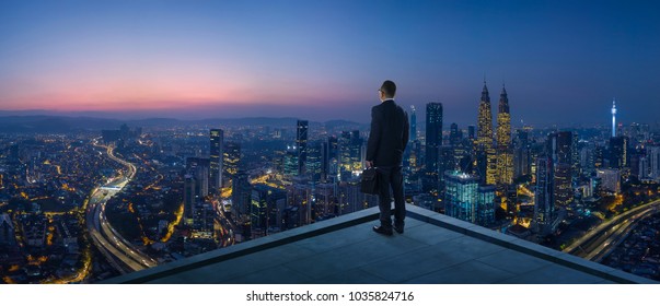 Businessman stand at rooftop looking great cityscape view and thinking business plan of the future . Night scene . - Shutterstock ID 1035824716