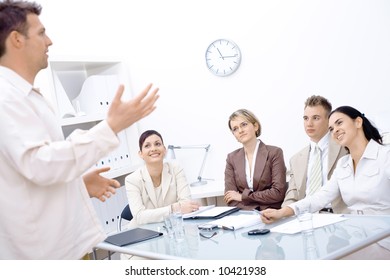 Businessman standing and explaining to four colleagues sitting in front of.