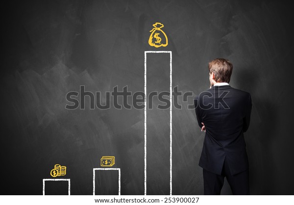 businessman standing in front of a\
blackboard with a chart about different types of\
wages