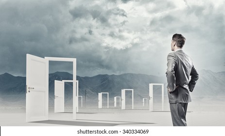 Businessman standing in front of opened doors and making decision - Shutterstock ID 340334069