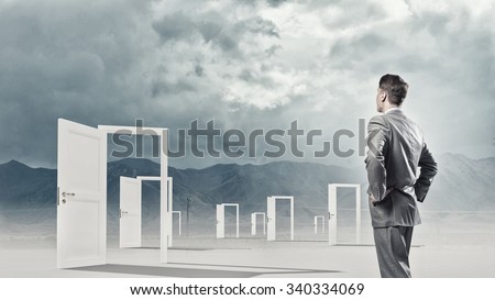 Businessman standing in front of opened doors and making decision
