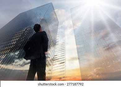 Homme d'affaires debout, les mains sur les hanches, face à la vue en basse angle des gratte-ciels au coucher du soleil