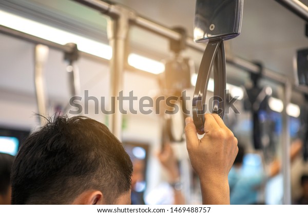 Businessman standing and holding handle on the\
skytrain bts go to work in the\
morning.