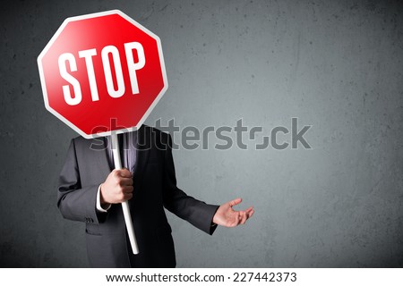 Businessman standing and holding a stop sign in front of his head