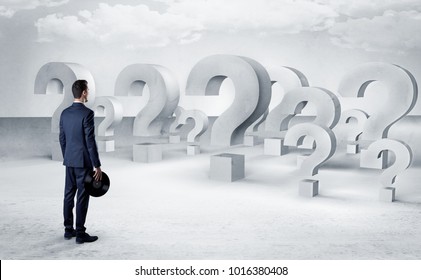 Businessman standing and looking to a bunch of question mark signs