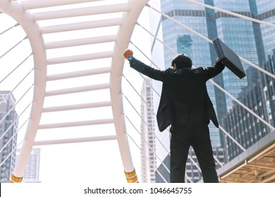 Businessman Standing In The Middle Of The City Is Happy To Succeed In His Work. He Lifts His Arms Up To The Sky,Copy Space.