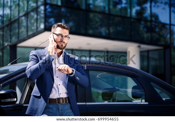 Businessman standing near the car. Office\
building on the\
background
