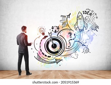 Businessman is standing near sketch with icons of rocket launch, start up, light bulb, globe, bar and pie diagrams, teamwork, plan and arrow. Concept of inspiration and imagination for creative idea
