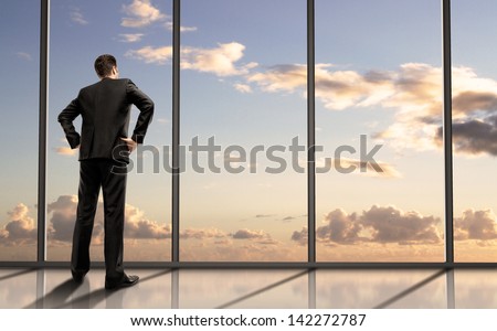 businessman standing in office and looking in sky