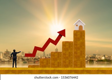 Businessman Standing On The Gold Bar And Red Arrow Graph With Grow Value And Looking To Future For New The Business Investment Opportunity And Home On The City Background, Fund Of Real Estate Concept.