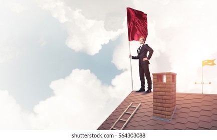 Businessman standing on house roof and holding red flag. Mixed media - Shutterstock ID 564303088