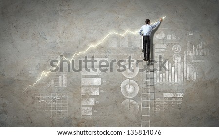 businessman standing on ladder drawing diagrams and graphs