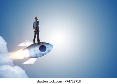 Businessman standing on launching rocket on abstract gray background with copy space. Start up and entrepreneurship concept 