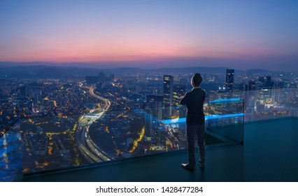 Businessman standing on open roof top balcony watching city night view . Business ambition and vision concept . - Shutterstock ID 1428477284
