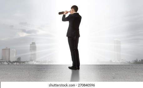 Businessman standing on a on road and looking through a telescope at city - Powered by Shutterstock