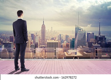 businessman standing on roof and looking at city - Powered by Shutterstock