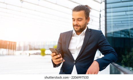 Businessman Standing Outdoor Use Smartphone Looking Device Screen And Smile. Handsome Hispanic Male Business Person Middle Age Dressed Business Suit Holding Smartphone In Hand. Modern Business Person