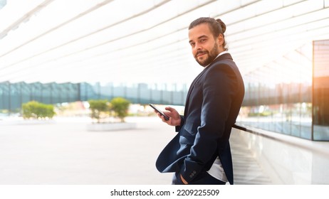 Businessman Standing Outdoor Use Smartphone Looking Camera Screen Confident. Handsome Hispanic Male Business Person In Business Suit Holding Smartphone In Hand. Modern Business Person Low Angle View