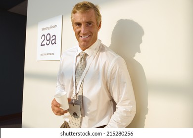 Businessman Standing Outside Meeting Room, Taking Coffee Break, Casting Shadow On Wall, Smiling, Portrait