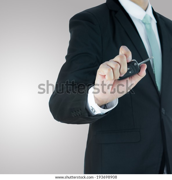 Businessman standing posture hand key for car\
isolated on over gray\
background