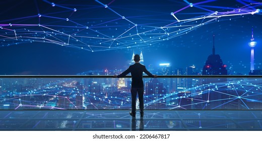 Businessman standing at rooftop with Smart night city view. Business success with smart big data technology concept - Shutterstock ID 2206467817
