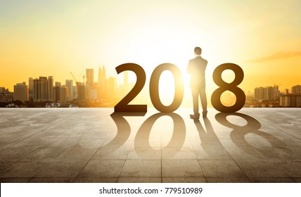 Businessman standing with sunset cityscape background. Ambitions, happy new year 2018 concept.