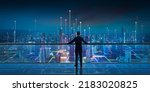 Businessman standing at transparent glass floor on rooftop with night Smart city panoramic view. Business success with smart technology concept