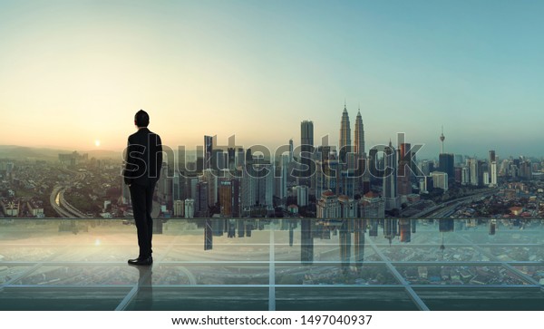 Businessman standing at\
transparent glass floor on rooftop with city skyline, success and\
thinking concept  .