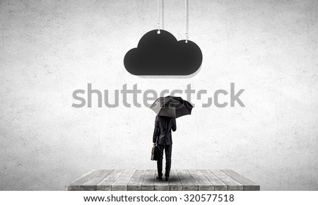 Businessman standing with umbrella under cloud concept