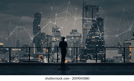 Businessman standing using smartphone in modern space watching city night view.Business Wireless network and Connection technology concept. - Powered by Shutterstock