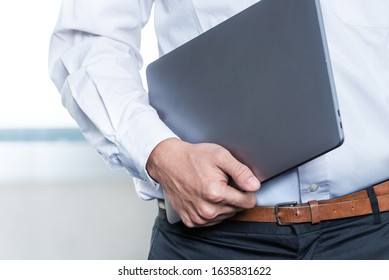 Businessman Standing While Carrying A Laptop On The Workplace