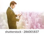 Businessman standing while using a tablet pc against low angle view of skyscrapers