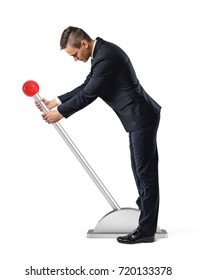 A businessman stands at a large lever with a red round knob and starts to move it. Start your business. Jump-start your career. Hands-on approach. - Shutterstock ID 720133378