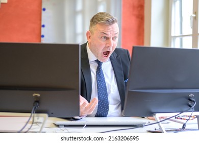 Businessman staring at his computer with stupefication and his mouth wide open in shock